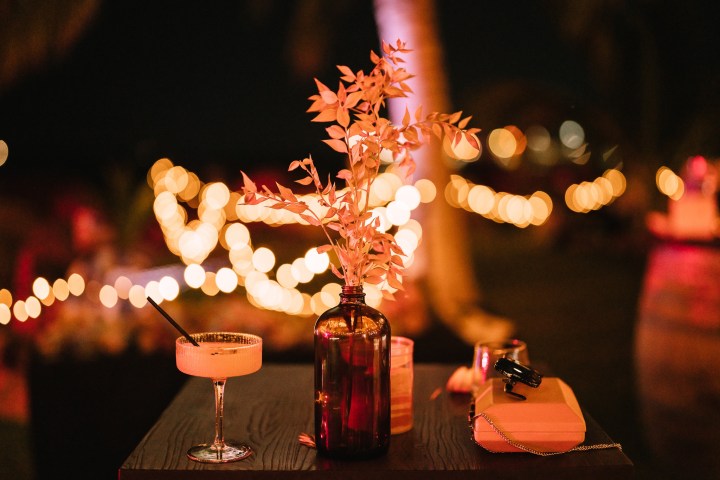 Night scene with cocktail, vase, and bokeh lights on a table.