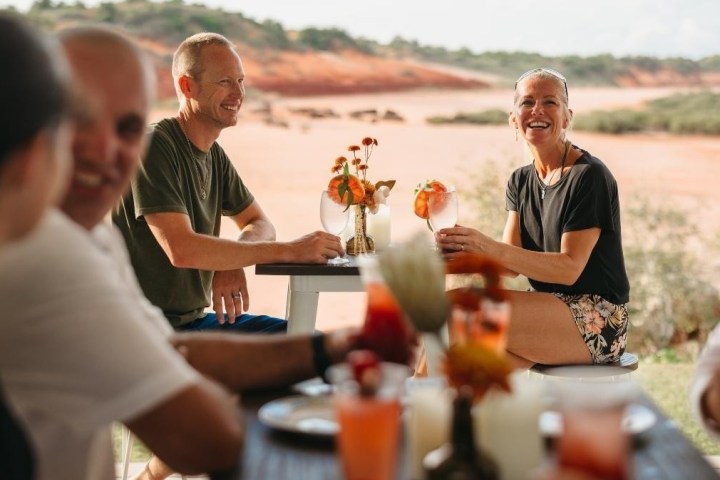 Five people enjoying drinks at an outdoor table with a scenic desert backdrop.