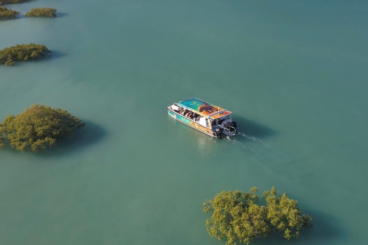 Aerial view of a boat navigating through a turquoise lake with small islands.